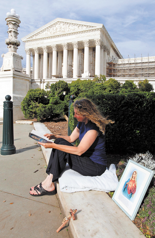 Carol Anderson of Williamsburg, Va., reads as she is the first person in line to attend today’s reading of the decision at the U.S. Supreme Court on the constitutionality of the Affordable Care Act. She started the line Wednesday afternoon.
