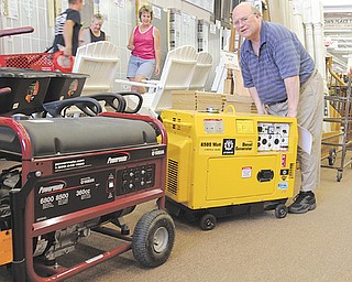 Bill Clark, manager of Bernard-Daniels Lumber and Hardware in Canfield wheels a diesel generator from the business, while a gas-powered generator sits on the floor. The company had put its generators on eBay Sunday night and sold several to people affected by the outages in central Ohio.