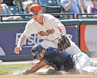 Tampa Bay Rays’ Carlos Pena, bottom, slides into third with an RBI triple as the throw eludes Cleveland Indians third baseman Jack Hannahan in the ninth inning of a baseball game Sunday in Cleveland. The Rays scored three runs in the inning off Indians closer Chris Perez to win 7-6.