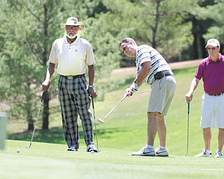 Former Steelers defensive end LC Greenwood, left, watches as Eric Folsom putts on No. 10 at Monday’s Circle of Friends Celebrity Golf Classic at the Lake Club in Poland. At right, Rob Folsom looks on.