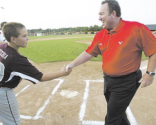 Steve Gillispie, YSU’s new baseball coach, shakes hands with Boardman catcher Dominic Pecchia after throwing out the first pitch on Wednesday at the Little League district championship game. Boardman defeated Austintown, 12-11, to earn a trip to state.
