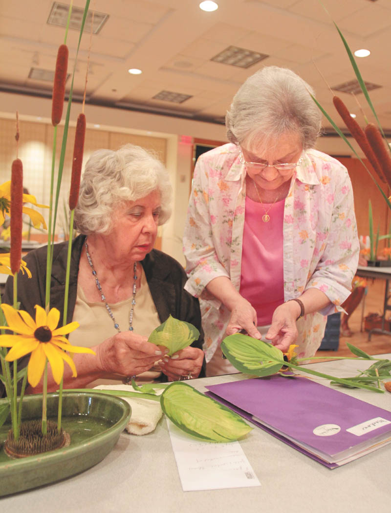 Shirley Winkler of Saxonburg, Pa., right, assists Pearl Marlos of Campbell as she creates a floral arrangement in the style of Ichiyo, one of numerous schools of Ikebana. Winkler has been teaching Japanese flower arranging for more than 30 years. Photo by: Robert K. Yosay | The Vindicator
