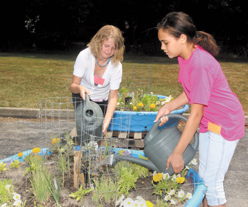 Ashlee Sedmond, left, and Jadyn Atwood, both of Boardman, work on their container garden at Pleasant Grove Presbyterian Church’s Camp Newport. Children who attend the Boardman camp participate in a variety of activities and are served lunch. Woodside Elementary in Austintown is host to a sister camp.