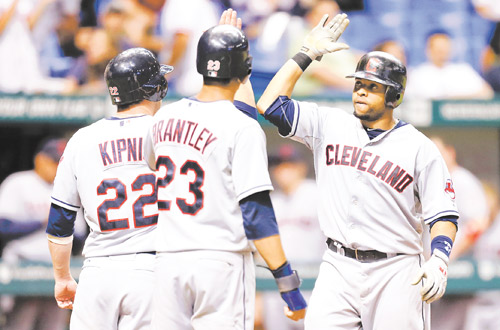 Indians slugger Carlos Santana, right, celebrates with teammates Jason Kipnis and Michael Brantley after hitting a seventh-inning three-run home run off Tampa Bay Rays relief pitcher Jake McGee during Wednesday’s baseball game in St. Petersburg, Fla. The Indians scored five runs in the seventh to rally past the Rays, 10-6.