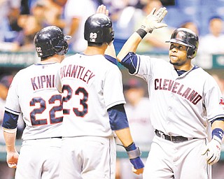 Indians slugger Carlos Santana, right, celebrates with teammates Jason Kipnis and Michael Brantley after hitting a seventh-inning three-run home run off Tampa Bay Rays relief pitcher Jake McGee during Wednesday’s baseball game in St. Petersburg, Fla. The Indians scored five runs in the seventh to rally past the Rays, 10-6.