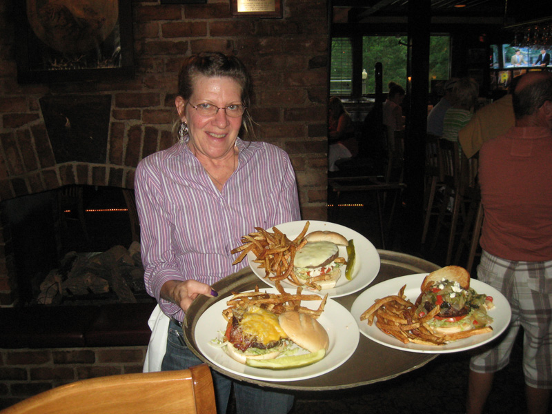 Barby Ferraro serves up some tasty Iron Bridge Inn burgers. Clockwise from left are The Western Burger, The Pittsburger and the Big Greek Burger.