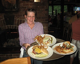 Barby Ferraro serves up some tasty Iron Bridge Inn burgers. Clockwise from left are The Western Burger, The Pittsburger and the Big Greek Burger.