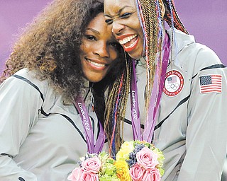 Serena Williams, left, and Venus Williams of the United States laugh together on the podium after receiving their gold medals in women's doubles at the All England Lawn Tennis Club in Wimbledon, London at the 2012 Summer Olympics, Sunday, Aug. 5, 2012. (AP Photo/Elise Amendola)