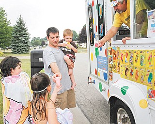 James Naughton, 2, Abbigail Yavorski, 7, and Lilly Naughton, 6, receive their treats from ice-cream truck vendor Joe Harrison after a swim in their pool.