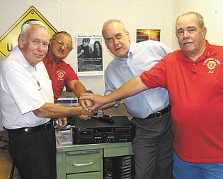 Using a symbolic gesture to represent a partnership of three decades between Canfield Lions Club and Youngstown Radio Reading Center are, from left, Ted Filmer, Lions past district governor; Harry Pancher, Lion; Mike Bosela of the center; and Ed Ellis, Lion. The club recently bought a new cassette recorder for the center to replace old equipment. The center broadcasts articles specifically for the sight impaired; Linda Ellis is a reader. Other Lions involved in the presentation were Marilyn Schmidt and Joan Filisky.