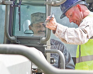 Reinhard Schmidt sits in a work vehicle while Master Sgt. Mike Brady shows him how it all works.