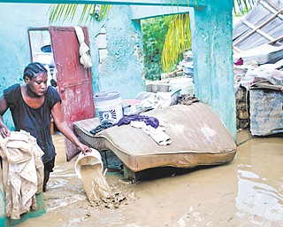 Finanette Guerrier, 29, bails muddy water from her fl ooded house after the passing of Tropical Storm Isaac in Port-au-Prince, Haiti, on Sunday. The death toll in Haiti from the storm has climbed to at least 10 after an initial report of four deaths, the Haitian government said Sunday.