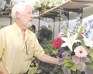 Gary Doles, owner of Bloomin’ Crazy Florist, looks over an arrangement at his Boardman business. Doles said
every business, including those online, should have to pay sales tax.