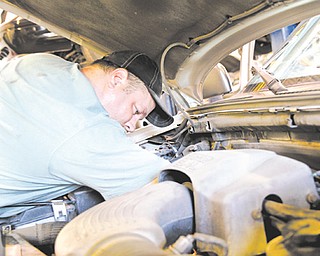 Ray Kelly, a Mahoning County mechanic, works on the engine of a county vehicle at the sanitary engineer’s office, 761 Industrial Road, Youngstown, where fueling and maintenance are centralized to save money.