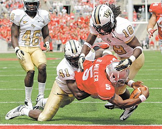 Ohio State’s Braxton Miller (5) scores a touchdown between Central Florida’s Terrance Plummer, left, and Kemal Ishmael during the third quarter of a game Saturday in Columbus. Ohio State won 31-16.