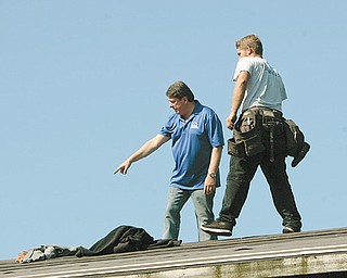 Sam Boak, of Boak & Sons Inc., inspects the roof of a Zander Drive home with Jason Brinsey of Boardman. Boak’s company is one of the main donors for an HBA community project to remodel the home.