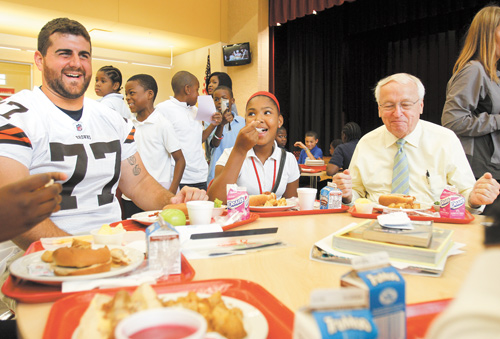 John Greco, left, a Cleveland Browns offensive lineman and Boardman native, and Kevin Concannon, the United States Department of Agriculture food and nutrition service undersecretary, eat lunch with Calayla Abron, a seventh-grader at Youngstown’s Wilson Middle School. Concannon joined Wilson students for lunch Tuesday to talk about the new guidelines for school lunches, which require healthier options.