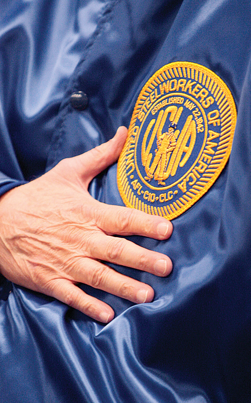 Mike Carney, former president and district director of the United Steelworkers of America, shows off the USW patch as he pauses for the national anthem at an event in Campbell on Wednesday commemorating the 35th anniversary of Black Monday.