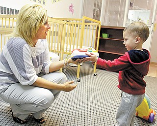 Holly Metzinger, administrative director at Great Expectations Learning Center in Hubbard, shows a toy to 1-year-old Brayden Frazzini. The learning center had an open house Tuesday night so families could see its new location for toddlers and infants.