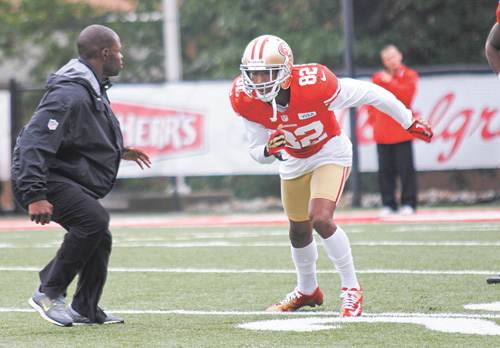 San Francisco 49ers wide receiver Mario Manningham (82), of Warren, participates in a drill during practice Wednesday at Stambaugh Stadium. Assistant coach Ejiro Evero, left, watches.