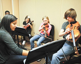 Gia DeAscentis, a Youngstown State University student, teaches a music class to Garfield Johnson, left, Ava Tovarnak, Alanna Clapp and Nathan Clapp at the SMARTS Center.
