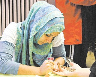 Lamia Sassya of Boardman draws henna art on hands during the Masjid Al-Khair mosque open house in Youngstown on Sunday.