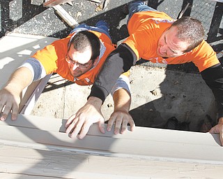 Home Depot volunteers Jason Weiser, left, of Boardman and Tim Hephner of Hermitage, Pa., install siding Thursday at the AMVETS Post 44 Career Center on Elm Street in Struthers. The project was financed by a $15,500 Home Depot grant.