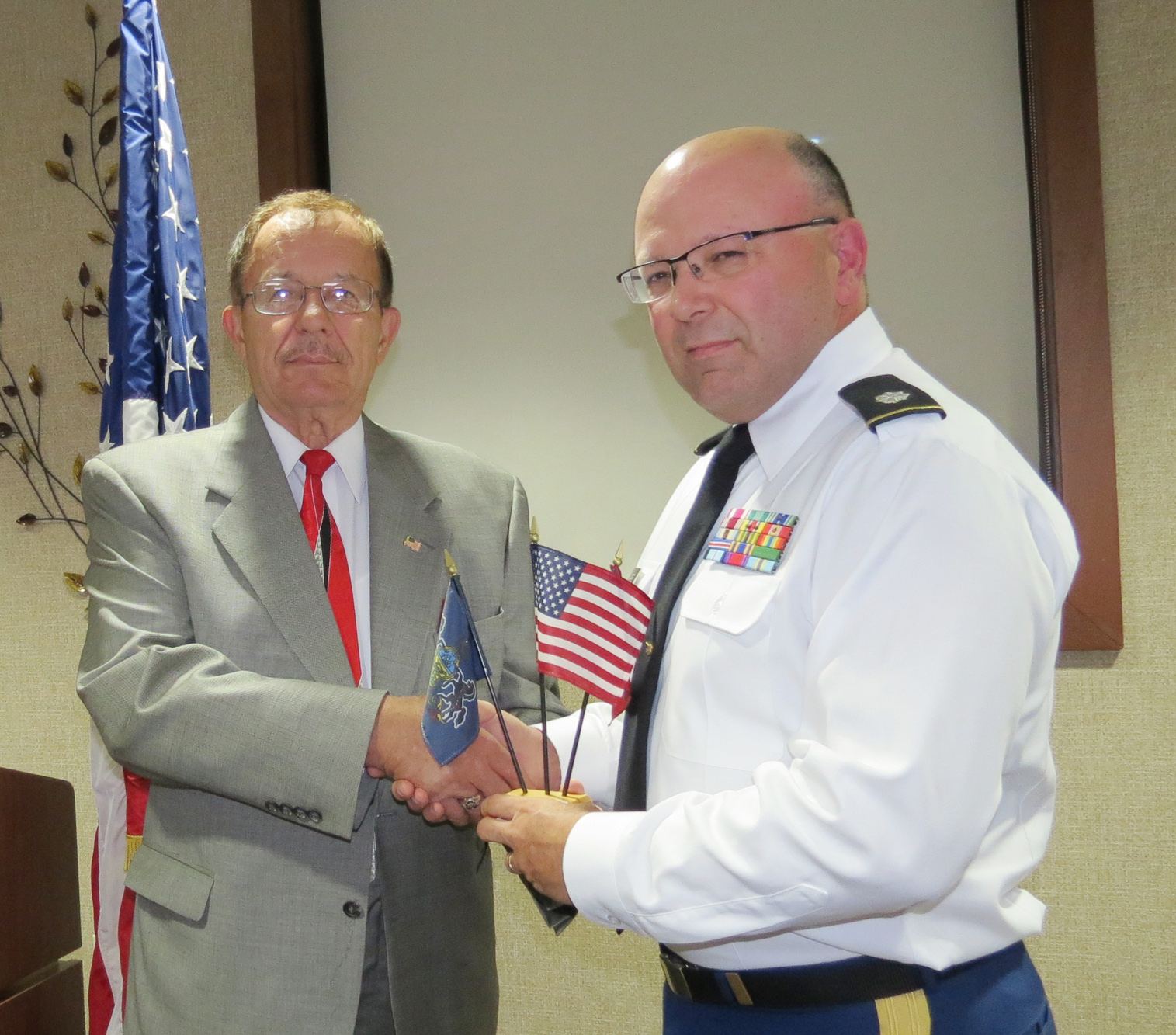 Col. Walter Duzzny, USA, retired, president of the Mahoning and Shenango Valleys Chapter of the Military Officers Association of America, presents Lt. Col. William Meade, Ohio National Guard, with a desktop flag set representing the U.S. Flag and the state flags of Pennsylvania and Ohio.