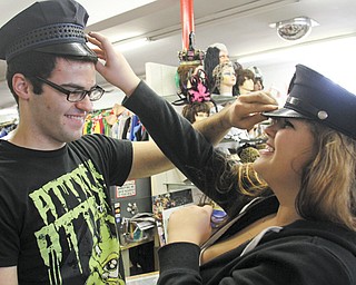 Matthew Davis of Cortland and Elise Campbell of Warren try on police hats at Ward’s Costume Shoppe in Niles. Spending for Halloween is increasing.