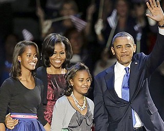 President Barack Obama waves as he walks on stage with first lady Michelle Obama and daughters Malia and Sasha at his election night party Wednesday night in Chicago after defeating Republican challenger former Massachusetts Gov. Mitt Romney.