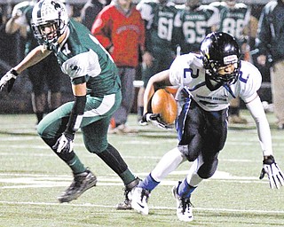 Youngstown Christian’s Darrien Townsend (2) keeps his balance after being hit by Malvern’s Nick Mohr (1) during the second quarter of Friday night’s Division VI regional semifinal at Akron St. Vincent St. Mary High School in Akron. YCS won, 25-20.