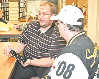 George Garrett, left, demonstrates new technology to Greg Stevens at the Girard library. Local libraries are taking advantage of new technology to make information accessible to the public.