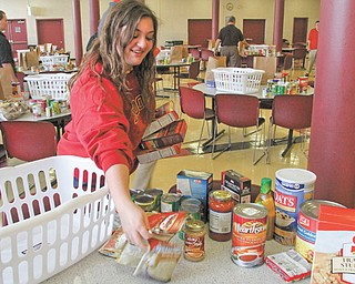 Monica Mattiussi of Cardinal Mooney High School helps to sort food items to be distributed to the needy. Students packed the baskets after school Monday, and juniors and seniors will deliver the baskets to Catholic Charities today for distribution to families.