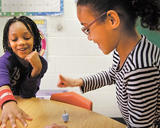 Manny Rivera, left and Kayla Paez, first-graders at Akiva Academy in Youngstown, spin dreidels in their classroom. The students will participate in “Light,” a community Hanukkah program Thursday.