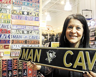 Touchdown Gifts owner Stephanie Mansour holds a Pittsburgh Penguins “Man Cave” sign in her store in Boardman’s Southern Park Mall. Hockey merchandise sales are way down because of the lockout.