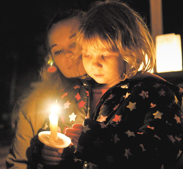 Cara Kowalczyk, left, and Michelle Peterson, 4, of Lordstown, reflect on the victims of Friday’s Newtown, Conn.,
elementary school massacre. The two attended a vigil in Founder’s Park in Lordstown on Sunday evening.