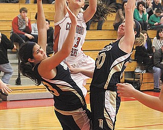 Columbiana’s Megan Cutlip (23) drives to the hoop between Lowellville defenders (30) Madison Opritza (30)
and Katie Seidita (43) during their game Monday in Columbiana. The Rockets clipped the Clippers, 52-47.