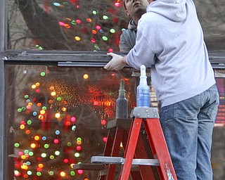 William d Lewis The Vindicator Anthony Palumbo gen mgr of Dooneys Sports Bar, washes windows infront of his establishment as city Christmas Tree is reflected in window.