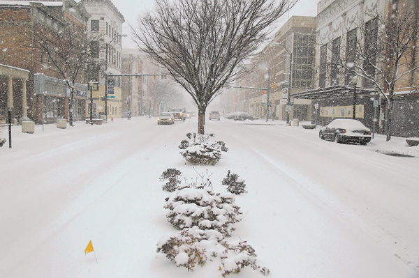 Cars inch their way through the accumulating snow on West Federal Street on Wednesday. The storm that was estimated to bring 8 to 12 inches by today closed libraries and government offices, but some businesses on West Federal stayed open to give walkers a warm place to go.