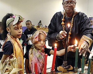 William D Lewis the Vindicator Lynnette Kimako Miller, right, watches as sisters Mercedes , 8, left, and Aniaya Dykes light candles during Kwanzaa celebration Tuesday at McGuffey Centre. Miller was one of the coodinators of the event.