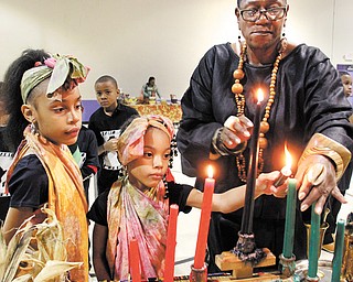 Lynnette Kimako Miller, right, a local Kwanzaa event coordinator, watches as Mercedes Dykes, 8, left, and her sister and Aniaya, 6, light candles during the final day of Kwanzaa. The McGuffey Centre hosted an event
Tuesday on the final day of the seven-day holiday.