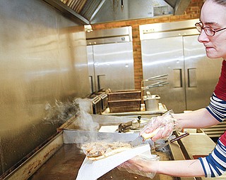 Nicole Brooks, left, prepares a gyro at Walrus Subs on Raccoon Road in Austintown. She and owner Alie Ruheim
have worked together for a year, and she says the restaurant is a “home away from home” for her.