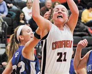 Canfield’s Rachel Tinkey (21) goes up for a layup as she is defended by Poland’s Kasie Serich (32) during the
first quarter of their All-American Conference American Division basketball game Thursday at Canfield High School. The Cardinals routed the Bulldogs, 56-18.