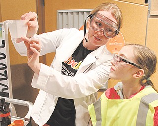 Holly Eberly, 11, right, a member of Girl Scout Troop 80420, of Canfield, watches Audra Carlson, OH WOW! education manager, during a science program at OH WOW! The Roger & Gloria Jones Children’s Center for Science & Technology in downtown Youngstown.