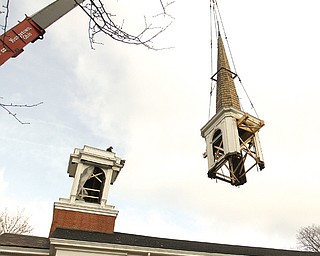 Slow and steady is the pace as parts of the steeple, the spire and lantern are moved by a crane from the roof of First Unitarian Universalist Church, 1105 Elm St., Youngstown, to the ground Tuesday. The spire will be stored, but the lantern and louvre, the wooden structure remaining on the church roof, will be demolished because they are beyond repair.