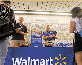 Wal-Mart employees Jon Christians and Lori Harris take job applications and answer questions during a job fair at the University of Illinois Springfield campus in Springfield, Ill. Wal-Mart Stores Inc., the world’s largest retailer and nation’s largest private employer, said Tuesday it is making a pledge to boost its sourcing from domestic suppliers and hire more than 100,000 veterans.