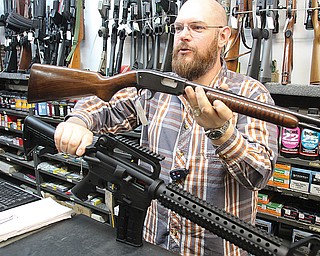 Miller Rod & Gun spokesman Mike Miller holds up two guns that look very different but can fire the same caliber of bullet. On the bottom, he is holding a Mossberg semiautomatic .22 long rifle with a 25-round capacity, and on the top is a Rossi pump-action .22-caliber rifle with a 17-round capacity.