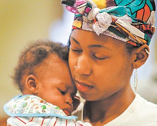 Mariah Wilson of Youngstown holds her 4-month-old son, Daniel Graham Jr., during a prayer at the Associated Neighborhood Center’s seventh annual citywide baby shower that took place Monday at the McGuffey Centre in Youngstown.