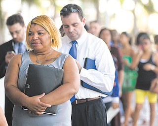 In this Jan. 15 photo, Racheel Weston stands in line with a few hundred other job-seekers during a job fair hosted by the Miami Marlins at Marlins Park in Miami. The number of Americans seeking unemployment
benefits fell last week to the lowest level in fi ve years, a positive sign that layoff s have fallen and hiring
may pick up.