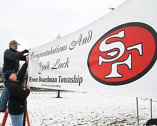 Mike Hardie and Ron Gorski hang up a banner supporting the San Francisco 49ers on Monday in front of the Boardman Township Government Center on Market Street. The banner was paid for out-of-pocket by township trustees. The 49ers take on the Baltimore Ravens on Sunday in the Super Bowl.